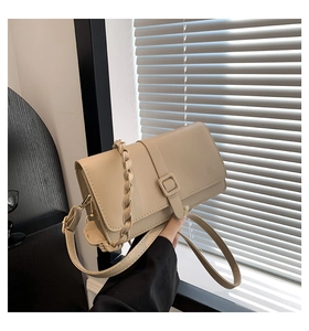 Détail du sac bandoulière crème avec poignée tressée et boucle carrée sous la lumière