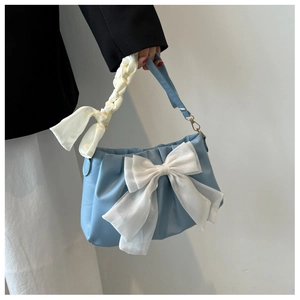 Close-up of sky blue shoulder bag with large white bow and ribbon handle detail