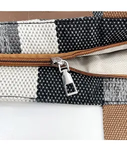 Detail of hand made leather tag and silver zipper on striped woven fabric bag