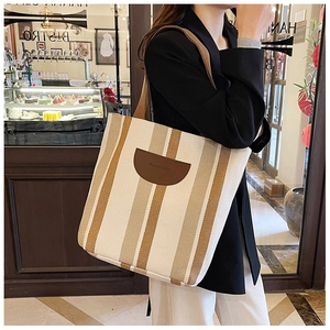 Detail showing high-quality striped canvas fabric and leather logo patch of the tote bag
