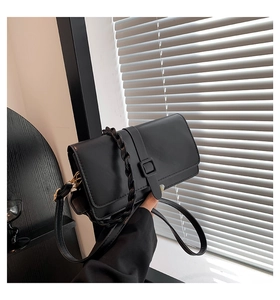 Détail du sac à bandoulière noir mat avec poignée tressée et boucle carrée élégante