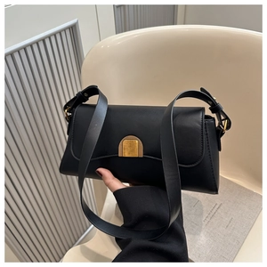 Detail of a black matte leather underarm bag with a central gold semicircular buckle