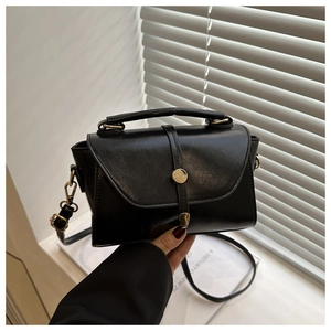 Close-up of black matte PU leather handbag with golden cylinder metal lock buckle
