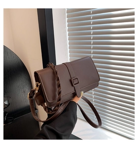 Détail d'un sac carré chocolat noir avec poignée tressée et boucles dorées