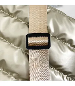 Detail of champagne gold quilted fabric with adjustable beige nylon shoulder strap buckle