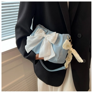 Detail of light blue shoulder bag with large white bow and pleated strap design