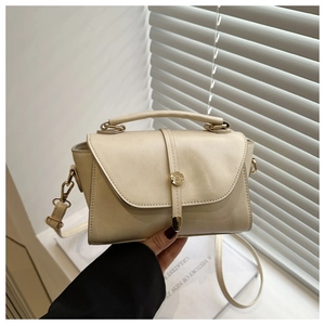 Detail of a creamy white mini square handbag with elegant gold buckle and smooth PU texture