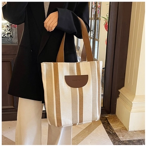 Close-up of striped canvas tote bag with Special Mail leather patch and wide handles