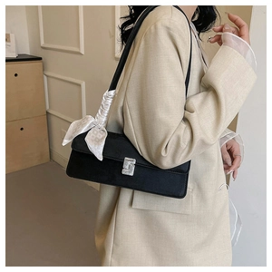Detail of black leather shoulder bag with silver S-buckle and elegant silk scarf accent