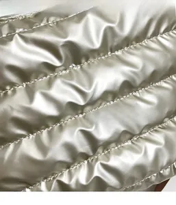 Detailed macro shot of silver metallic quilted fabric with premium horizontal stitching