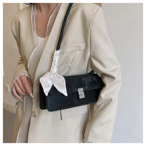 Detail of black suede shoulder bag with rhinestone buckle and checkered silk scarf
