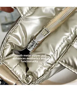 Macro shot of metallic gold puffer bag featuring a smooth metal zipper and polished hardware
