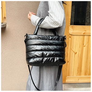 Close-up of a black quilted puffer tote bag with handles and adjustable shoulder strap