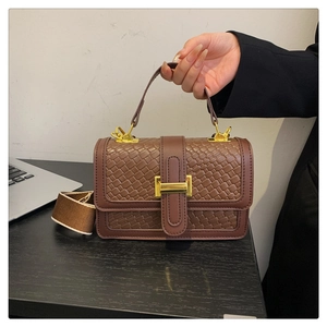 Détail d'un sac à main tissé marron avec fermoir doré et bandoulière large en toile