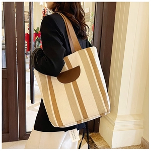 Detail view of striped canvas tote bag with brown straps and anti-theft security tag