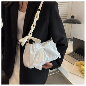Detail of white satin ribbon bow handbag featuring woven strap and elegant cloud pleats
