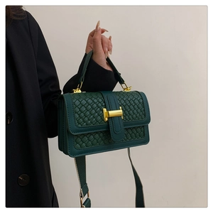 Détail de la texture en cuir tressé vert et boucle métallique dorée en forme de H chic