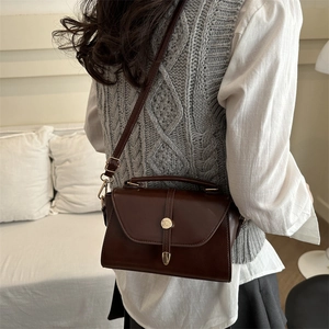 Vintage brown leather crossbody bag with gold buckle shown on a knit sweater outfit