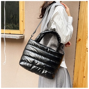 Detailed side view of black quilted puffer handbag featuring padded handle and strap