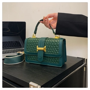 Détail du sac à main tissé vert foncé avec fermoir doré en H et large bandoulière en toile