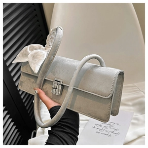 Close-up of a silver baguette bag with a sparkling S-shaped buckle and silk scarf detail