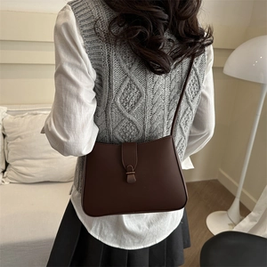 Minimalist dark brown leather crescent bag for women worn as an elegant shoulder bag