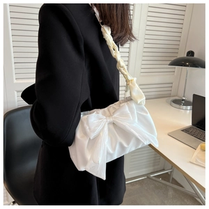 Detailed side view of white bow shoulder bag with pleated satin fabric on a model