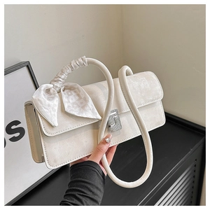 Detail of ivory faux leather shoulder bag with chic silk scarf bow and metal buckle