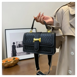 Détail du sac à main tressé noir avec surpiqûres blanches et boucle dorée chic