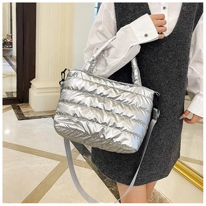 Silver quilted padded handbag shown with adjustable strap in a stylish indoor setting