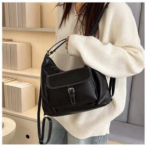 Gros plan sur un sac rétro en cuir noir avec surpiqûres blanches et boucle en métal argenté