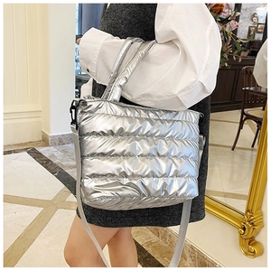 Detail view of a silver metallic quilted puffer tote bag with a removable shoulder strap
