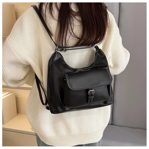 Détail d'un sac à dos en cuir noir avec surpiqûres contrastées et boucle métallique