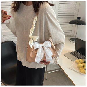 Detail of light brown pleated shoulder bag with large white bow and silk handle