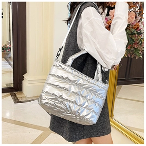 Close-up of a silver quilted puffer bag with metallic texture worn by a model