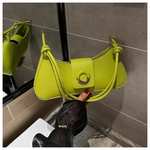 Detail of green leather underarm bag with circular metal buckle and knotted handle