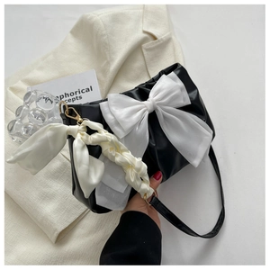 Detail of black pleated shoulder bag with large white mesh bow and silk scarf handle