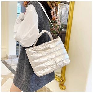 Detail of glossy silver quilted puffer tote bag with nylon shoulder strap and handles