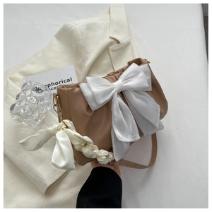 Detail of light brown crossbody bag with large white organza bow and woven silk handle
