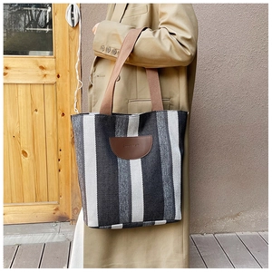 Outdoor lifestyle view of a large striped tote bag with leather handles and accents