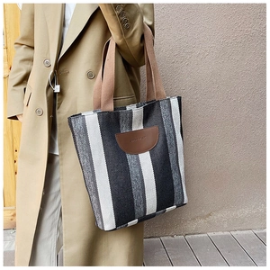 Detail of striped canvas tote bag with brown leather patch and sturdy woven handles