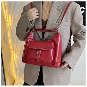 Vue détaillée du sac en cuir verni bordeaux montrant les coutures blanches et la boucle