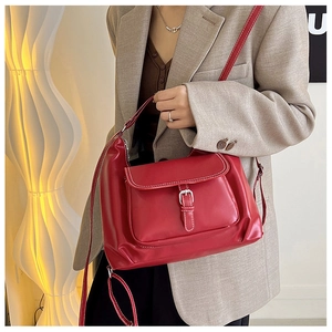 Détail d'un sac à bandoulière en cuir mat rouge avec surpiqûres et boucle métallique