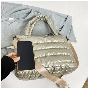 Champagne metallic quilted tote bag with wide strap compared to a smartphone for size