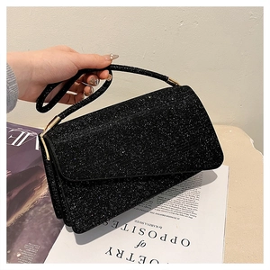 Vue détaillée du sac à main noir pailleté avec poignée métallique et texture scintillante
