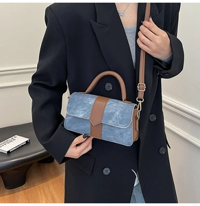 Detail van blauwe denim en bruine lederen stiksels op een kleine handtas