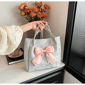 Detail der silbernen Samt-Einkaufstasche mit großer rosa Organza-Schleife und Griffen