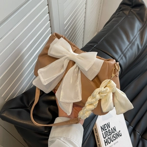 Brown leather shoulder bag with large white chiffon bow and woven handle strap