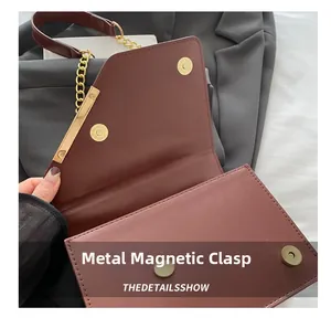 Macro shot of high-quality gold magnetic snap button and chain on burgundy leather bag