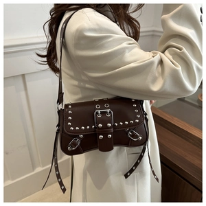 Détail du sac bandoulière en cuir marron avec rivets argentés et œillets métalliques